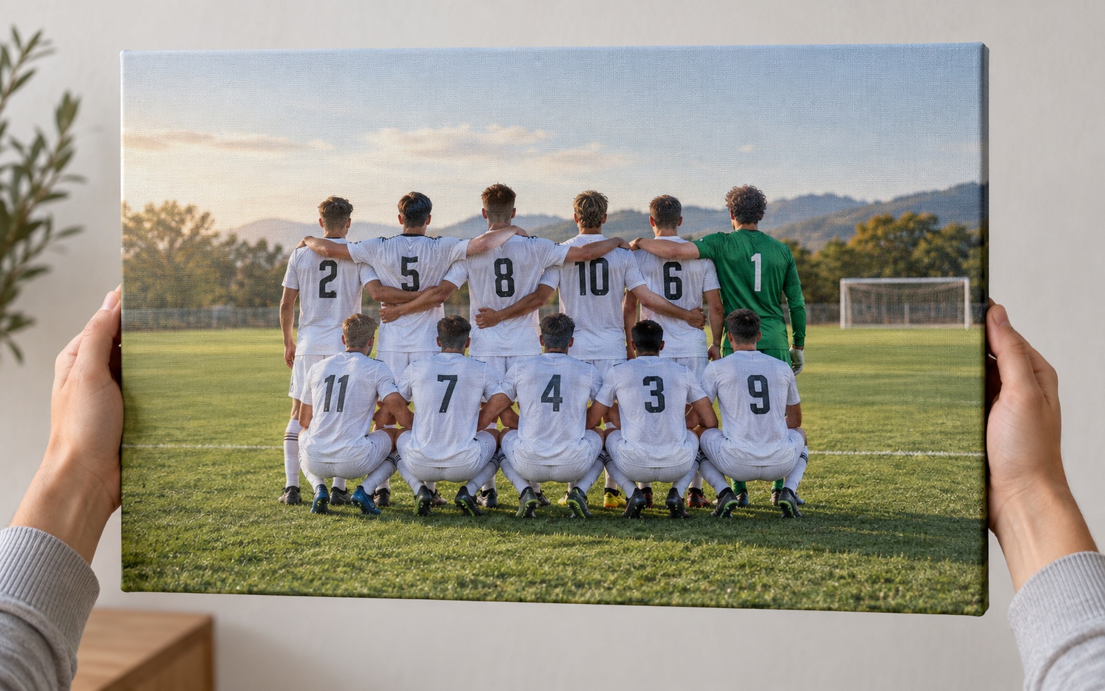 サッカーの集合写真を印刷した卒団記念キャンバスを持つ手元